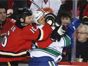 Vancouver Canucks' Andrew Alberts gets slammed into the boards by Calgary Flames' Brian McGrattan during first period NHL hockey action in Calgary on Dec. 29, 2013. It was Alberts' last game.