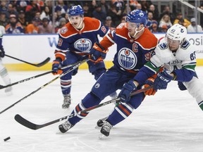 Jay Beagle of the Vancouver Canucks attempts to dislodge the puck from Edmonton Oilers' captain Connor McDavid during Thursday's NHL action in Edmonton.