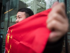 Yanggui Liu holds a Chinese flag outside B.C. Supreme Court during the third day of a bail hearing for Meng Wanzhou, the chief financial officer of Huawei Technologies.