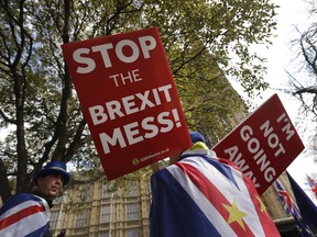 Anti-Brexit demonstrators hold placards outside Parliament in London, Thursday, March 28, 2019. British Prime Minister Theresa May is making a final effort to save her European Union withdrawal deal after her promise to quit failed to win over lawmakers from Northern Ireland. May pledged Wednesday night that she would stand down if the deal were approved, in hopes of blunting opposition from lawmakers who have criticized her leadership.