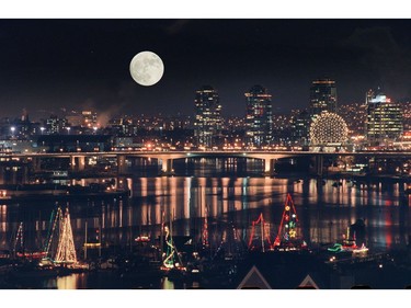 A full moon and city lights provide a dramatic backdrop as a parade of Christmas Carol Ships sets out for an evening cruise in the marine community of False Creek. With story by Yvonne Jeffery for CanWest travel package. For Doug Todd Christmas 2017 (Photo by Mark van Manen/Vancouver Sun)