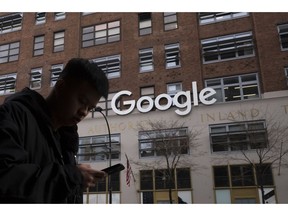 FILE - In this Dec. 17, 2018, file photo a man using a mobile phone walks past Google offices in New York. Google says it plans to launch a video-game streaming platform called Stadia, positioning itself to take on the traditional video-game business.