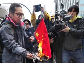 A protester sets fire to a Chineses flag as Huawei executive Meng Wanzhou appears for an extradition hearing at B.C. Supreme Court in Vancouver on March 6.