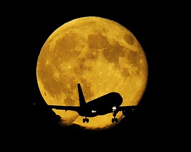 July 26,  2010  Spectacular full moon over the lower mainland hovers above a passenger jet ready to land at YVR in  Vancouver on July 26 2010.  The Moon is expected to still be showing with clear weather forecast.   (Mark van Manen/PNG)    see Full Moon  / Sun Cityside -stories )      [PNG Merlin Archive]