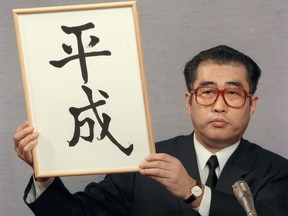 In this Jan. 7, 1989, photo, then Japan's Chief Cabinet Secretary Keizo Obuchi unveils the name of a new era "Heisei" during a press conference at the prime minister's official residence in Tokyo, following the death of Emperor Hirohito earlier that day. What's in a name? Quite a lot if you're a Japanese citizen awaiting the official announcement Monday. April 1, 2019 of what the soon-to-be-installed new emperor's next era will be called. It's a proclamation that has happened only twice in nearly a century, and the new name will follow Emperor Naruhito, after his May 1 investiture, for the duration of his rule, attaching itself to much of what happens in Japan.(Kyodo News via AP)