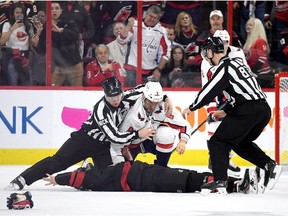 Linesman Scott Cherrey pulls Alex Ovechkin off of Andrei Svechnikov during the first period.