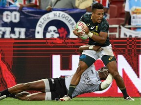 Fiji's Apenisa Cakaubalavu tackles South Africa's Angelo Davids (front) during the Singapore Rugby Sevens Cup final match between South Africa and Fiji in Singapore on April 14, 2019.