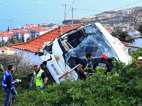 Firemen stand next to the wreckage of a tourist bus that crashed on April 17, 2019 in Caniço, on the Portuguese island of Madeira. - At least 28 people were killed when a tourist bus crashed on the Portuguese island of Madeira, the local mayor told local media. The regional protection service did not confirm the toll when questioned by AFP.