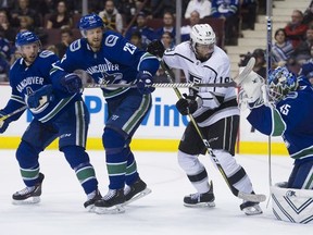 Alex Biega, Alex Edler and LA Kings Alex Iafallo look back at goalie Jacob Markstrom as the puck sails clear of the net in the second period of an NHL game on March 28 at Rogers Rean