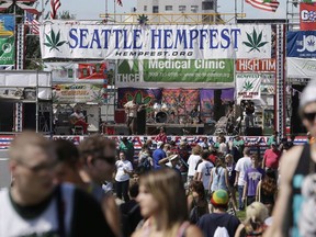 People walk past the main stage at the first day of Hempfest, Friday, Aug. 16, 2013, in Seattle. They both came from humble beginnings: small protests against marijuana prohibition where activists smoked weed in public, boldly defying what they considered an unjust law. But as Vancouver's 4-20 and Seattle's Hempfest grew into large-scale occasions with vendors, prominent musical acts and tens of thousands of attendees, the Canadian event has drawn scorn and opposition from elected officials, while American politicians have tolerated and even supported the gathering.