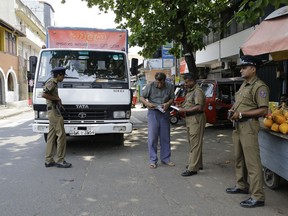 Sri Lankan police officers perform security checks on a truck at a roadside in Colombo, Sri Lanka, Thursday, April 25, 2019. Sri Lanka banned drones and unmanned aircraft and set off more controlled detonations of suspicious items Thursday four days after suicide bombing attacks killed more than 350 people in and around the capital of Colombo.