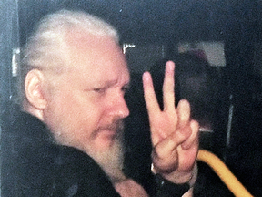 Julian Assange gestures as he arrives at Westminster Magistrates' Court in London, after the WikiLeaks founder was arrested on April 11, 2019.