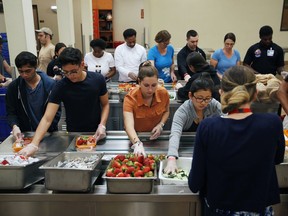 In this March 26, 2019, photo, volunteers put together food trays at Three Square, a food bank in Las Vegas. The reduction of food waste has taken hold in a city known for excess: Las Vegas. Sin City's world-famous casinos in recent years have developed and expanded innovative practices to cut back on the leftover and uneaten food they send to the landfill by thousands of tons a year. In 2016, MGM began donating fully cooked but never-served meals from conventions and other large events to Three Square, southern Nevada's only food bank.