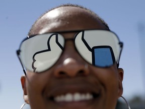 FILE - In this March 28, 2018, file photo, a visitor poses for a photo with the Facebook logo reflected on her sunglasses at the company's headquarters in Menlo Park, Calif. Facebook reports earnings Wednesday, April 24, 2019.