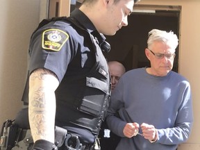 John Brittain is escorted from the RCMP detachment in Penticton, B.C., on Tuesday, April 16, 2019, in this image made from video.