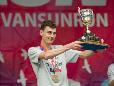 Burnaby's Justin Kent holds up the trophy after winning The Vancouver Sun Run in Vancouver on Sunday, April 14, 2019.