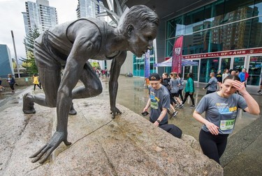 Runners take a break beside the Percy Williams statue outside B.C. Place Stadium after their runs are over at The Vancouver Sun Run on Sunday, April 14, 2019.