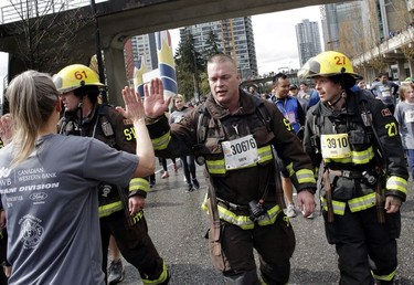 Did they actually run in this gear? Local firefighters high-five at the Vancouver Sun Run in Vancouver on Sunday, April 14, 2019.