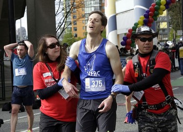 An exhausted Vancouver Sun Run participant gets some support from race officials after his run at the 35th annual event on Sunday, April 14, 2019.