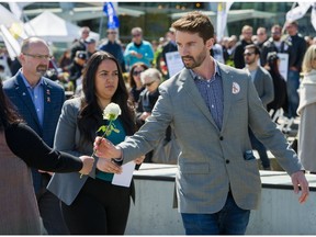 Injured worker Mike Shaw accepts a flower as hundreds of people attend a day of nourning at Jack Poole Plaza in Vancouver on April 28, 2019. The annual eventg commemorates workers who have been killed or seriously injured as a result of their job.
