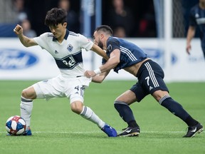 Vancouver Whitecaps' Inbeom Hwang, left, and Los Angeles Galaxy's Romain Alessandrini vie for the ball during the first half of an MLS soccer game in Vancouver, on Friday April 5, 2019.