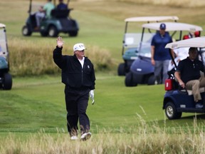 FILE - In this July 14, 2018 file photo, President Donald Trump waves to protesters while playing golf at Turnberry golf club, in Turnberry, Scotland. Trump's alleged misdeeds on and around the golf course are the subject of a new book by former sports columnist Rick Reilly, called "Commander in Cheat: How Golf Explains Trump." Reilly documents dozens of examples of exaggerations and underhanded play by the president. Reilly tells The Associated Press there have been "dozens and dozens of people that can declare him guilty of cheating."