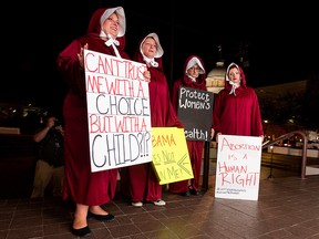 Protesters, dressed as handmaids, from left, Bianca Cameron-Schwiesow, Kari Crowe, Allie Curlette and Margeaux Hartline, wait outside of the Alabama statehouse after a ban on nearly all abortions passed the senate in Montgomery, Ala., on Tuesday, May 14, 2019.