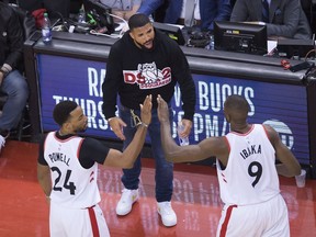 Toronto Raptors forward Norman Powell (24) and Raptors centre Serge Ibaka (9) celebrate with Drake, centre, while playing giants the Milwaukee Bucks during second half NBA Eastern Conference finals basketball action in Toronto on Tuesday,May 21, 2019.