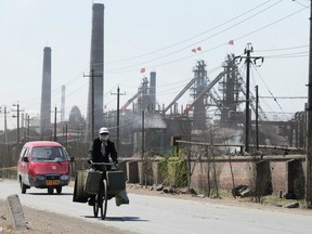 This file photo taken on April 21, 2011 shows a cyclist wearing a protective face mask while riding along a dusty road, where dozens of factories process rare earths, iron and coal operate, on the outskirts of Baotou city in Inner Monglia, northwest China.