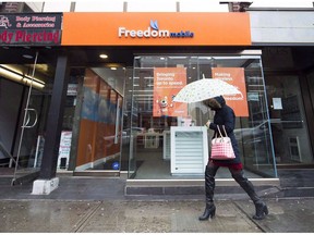 A women walks past the new rebranding sign of Freedom Mobile in Toronto on Thursday, November 24, 2016. Freedom Mobile says about 15,000 customers were affected by a security breach in a new system before the problem was fixed on April 23.