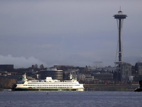 In this Dec. 27, 2018, file photo, a Washington State ferry heading into Elliott Bay is illuminated by the sun as the city behind remains under clouds in Seattle.. Authorities say a Washington State ferry struck a whale Tuesday night, May 28, 2019, during a sailing from Seattle to Bainbridge Island.