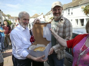 Labour Party leader Jeremy Corbyn, left, is gifted a spinach, asparagus and mushroom pie baked by local resident Gavin Williams who he met whilst out canvassing in Worthing, West Sussex, England, Wednesday, May 23, 2019 as voters head to the polls for the European Parliament election. Voters in Britain and the Netherlands are the first to cast their ballots in the four-day election for members of the European Parliament.