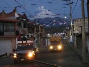 People drive through the streets in the village of Santiago Xalitzintla, Mexico, as the Popocatepetl volcano spews ash nearby.