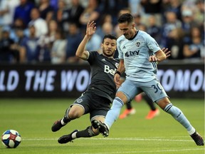 Sporting Kansas City midfielder Benny Feilhaber, right, is tackled by Vancouver Whitecaps midfielder Felipe Martins during the first half of Saturday's Major League Soccer match in Kansas City, Kan.