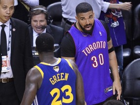 Rapper Drake, right, yells at Golden State Warriors forward Draymond Green (23) after the Toronto Raptors defeated the Warriors in Game 1 of the NBA championship basketball finals in Toronto on Thursday, May 30, 2019. THE CANADIAN PRESS/Nathan Denette