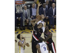 Portland Trail Blazers' Enes Kanter (00) shoots between Golden State Warriors' Andre Iguodala (9) and Stephen Curry, left, during the first half of Game 1 of the NBA basketball playoffs Western Conference finals Tuesday, May 14, 2019, in Oakland, Calif.