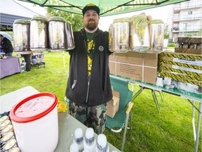 Mike Rutter of Cariboo Root Beer holds up his flavoured products Saturday at the fourth annual Root Beer Festival at Douglas Park in Langley.