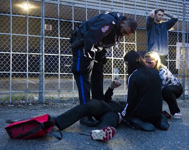 Friends and family comfort a man after he fell from a fence onto his head. Transit Police check the individual after a report he was in possession of many knives. The man tried to climb over a fence and fell after getting hung up on the fence.