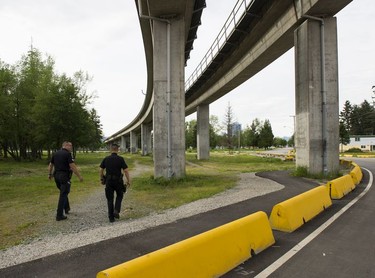 Transit Police Sgt. Clint Hampton (left) and Const. Darren Chua walk under the SkyTrain rails between Surrey Central and Gateway stations.