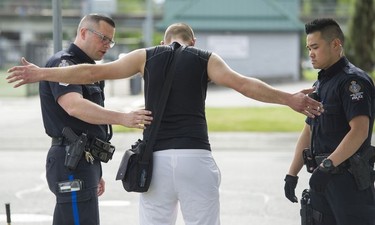 Transit Police Sgt. Clint Hampton (left) and Const. Darren Chua search a man suspected of drug trafficking after observing a hand to hand exchange near City Parkway.