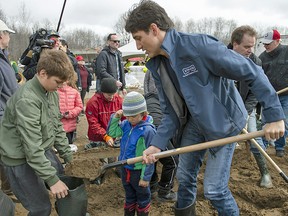 Wearing a Stelco jacket, Prime Minister Justin Trudeau fills sandbags with son Xavier as son Hadrien watches, in Constance Bay on Saturday, April 27, 2019.