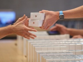 An Apple employee hands over Apple iPhone 7 phones on the first day of sales of the new phone at the Berlin Apple store on September 16, 2016 in Berlin, Germany.
