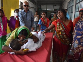 An Indian child arrives in a hospital due to Acute Encephalitis Syndrome (AES) as family members react in Muzaffarpur on June 10, 2019. -