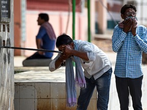 An Indian man drinks water from a roadside tap during a hot day in Churu, Rajasthan on June 4, 2019. - Temperatures in an Indian desert city hit 50 degrees Celsius (122 Fahrenheit) for the second time in three days as a deadly heatwave maintained its grip on the country. The thermometer hit 50.3 (122.54 Fahrenheit) in Churu in Rajasthan state, sending residents scrambling for shade to escape the searing sun.