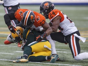 B.C. Lions Jordan Herdman-Reed and Chris Edwards, right, tackle Edmonton Eskimos Natey Adjei during Friday's CFL action in Edmonton. The Lions dropped to 0-2 after a 39-23 setback.