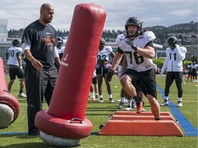 B.C. Lions Edward Godin runs through a drill under the watchful eye of Defensive Line coach Chris Ellis during the training camp at Hillside Stadium in Kamloops. Photo: Richard Lam/Postmedia