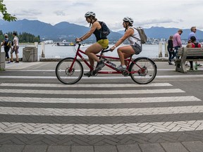Cyclists make their way along the seawall in Vancouver, BC.