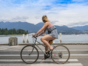 A cyclists takes in the view of the North Shore Mountains while riding along the seawall in Vancouver.