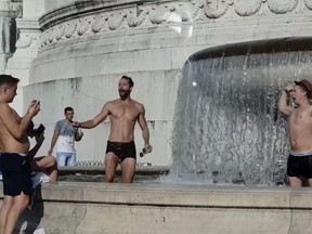 Two male tourists wander into a fountain just below the Tomb of the Unknown Soldier, bare chested.