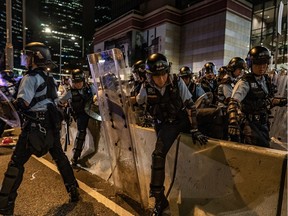 HONG KONG - JULY 2: Police officers charge toward anti-extradition protesters outside of the Legislative Council Complex on July 2, 2019 in Hong Kong, China. Thousands of pro-democracy protesters faced off with riot police on Monday during the 22nd anniversary of Hong Kong's return to Chinese rule as riot police officers used batons and pepper spray to push back demonstrators. The city's embattled leader Carrie Lam watched a flag-raising ceremony on a video display from inside a convention centre, citing bad weather, as water-filled barricades were set up around the exhibition centre.